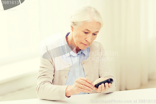 Image of senior woman with glucometer checking blood sugar