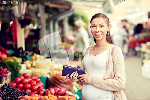 Image of pregnant woman with wallet buying food at market