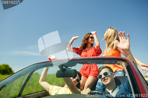 Image of happy friends driving in cabriolet car