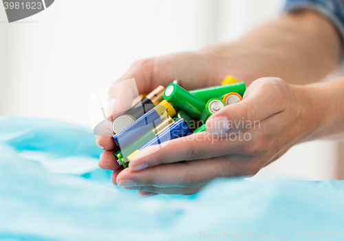 Image of close up of hands putting batteries to rubbish bag