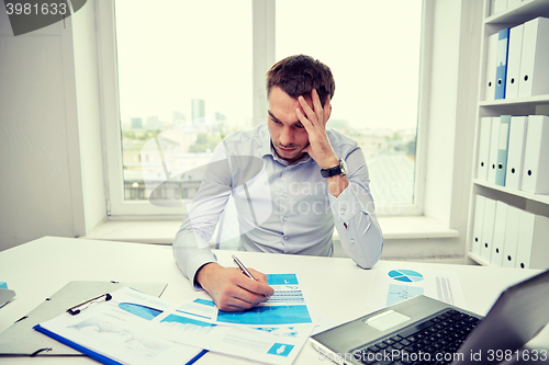 Image of stressed businessman with papers in office