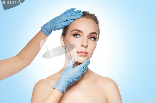 Image of surgeon or beautician hands touching woman face