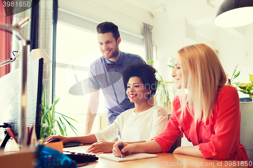 Image of happy creative team with computer in office