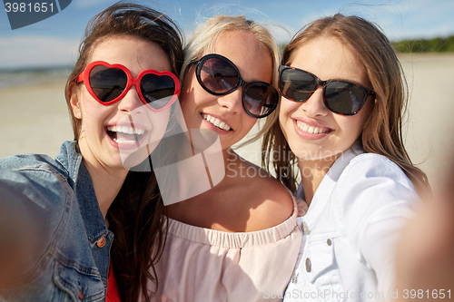 Image of group of smiling women taking selfie on beach