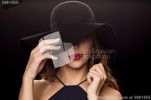 Image of beautiful woman in black hat over dark background