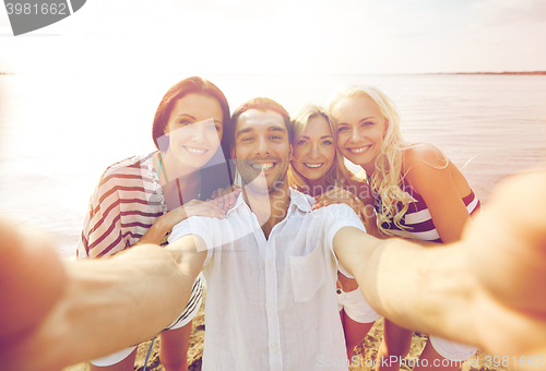 Image of happy friends on beach and taking selfie