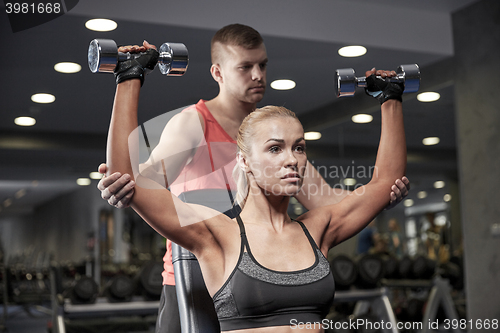 Image of man and woman with dumbbells in gym