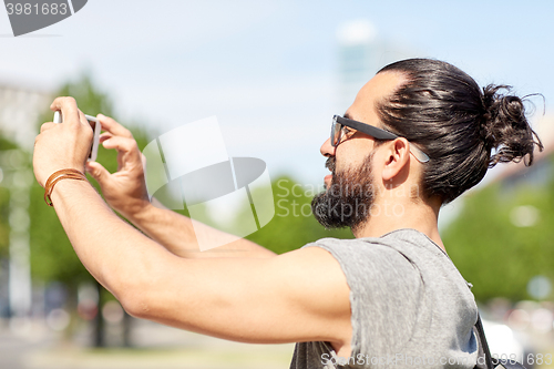 Image of man taking video or selfie by smartphone in city