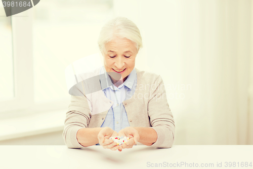 Image of happy senior woman with medicine at home