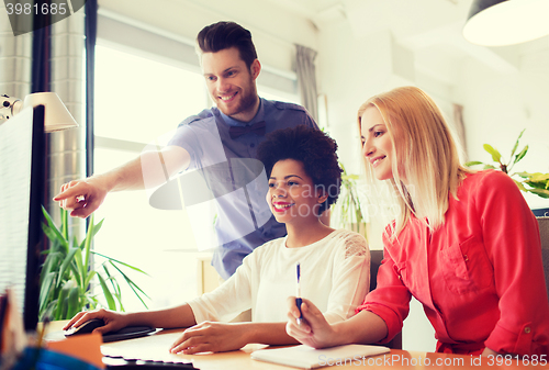 Image of happy creative team with computer in office