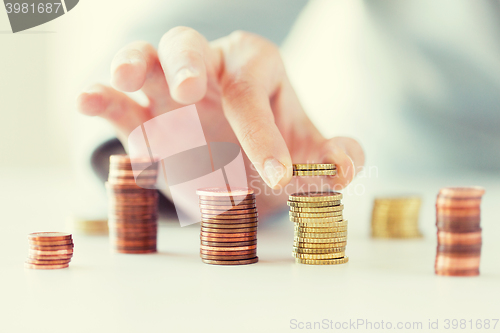 Image of close up of female hand putting coins into columns