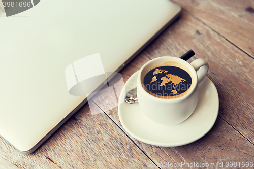 Image of close up of laptop and coffee cup with world map