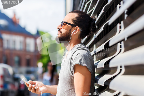 Image of happy man with earphones and smartphone in city