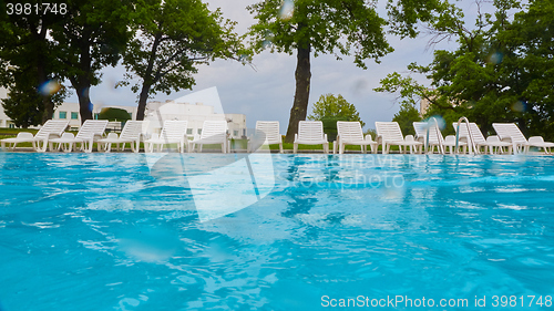 Image of wimming pool with blue water and empty sunbed