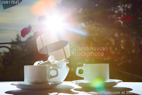 Image of white teapot, two cups and sun. Garden party.