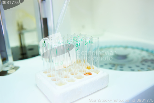 Image of pipette dropping sample into a test tube,abstract science background