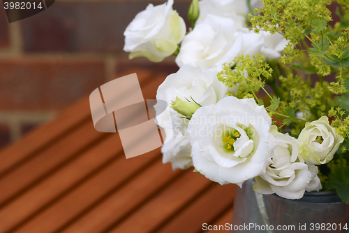 Image of White tulip gentians with ladys mantle on a wooden table