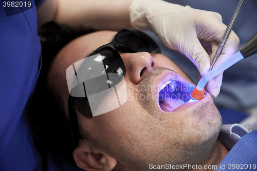 Image of close up of male patient with dental curing light