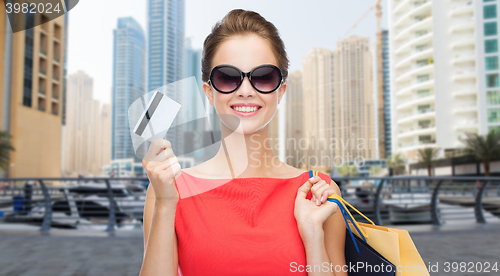 Image of woman with shopping bags and credit card over city