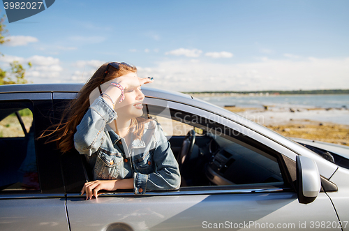 Image of happy teenage girl or young woman in car