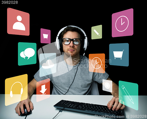 Image of man in headset with computer and icons on screen