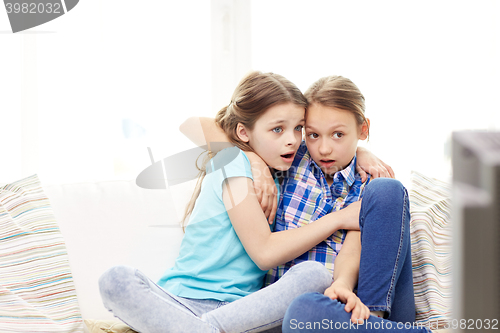 Image of scared little girls watching horror on tv at home