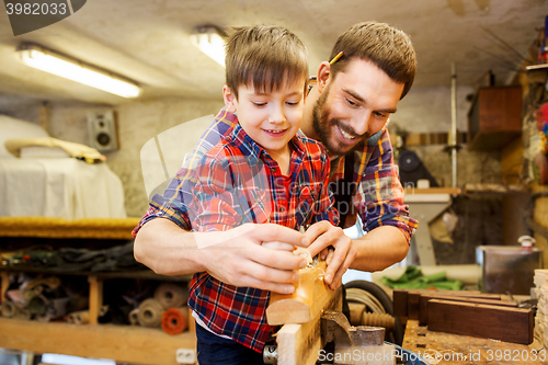 Image of father and son with plane shaving wood at workshop