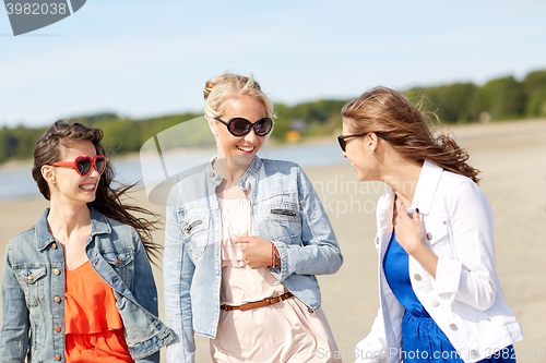 Image of group of smiling women in sunglasses on beach