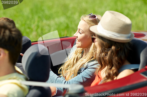 Image of happy friends driving in cabriolet car