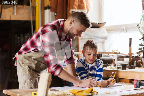 Image of happy father and son with blueprint at workshop