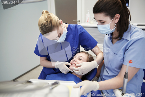 Image of happy female dentist with patient girl at clinic