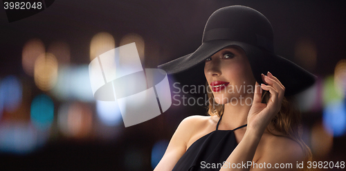 Image of beautiful woman in black hat over night lights