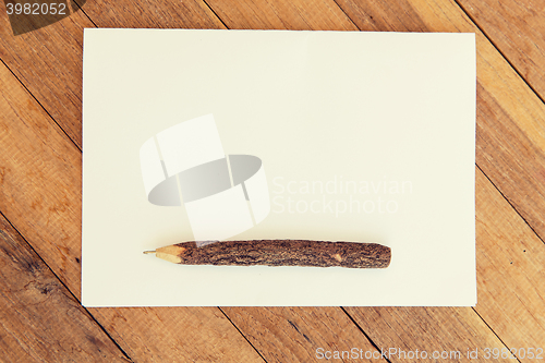 Image of white blank paper sheet with wooden pen on table 