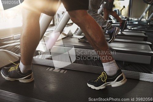 Image of close up of men legs walking on treadmills in gym