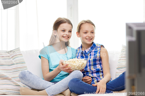 Image of happy girls with popcorn watching tv at home