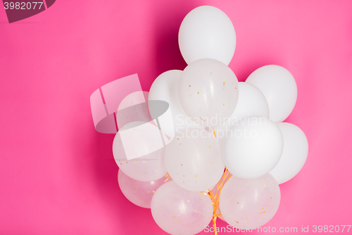 Image of close up of white helium balloons over pink