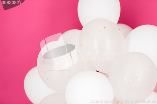 Image of close up of white helium balloons over pink