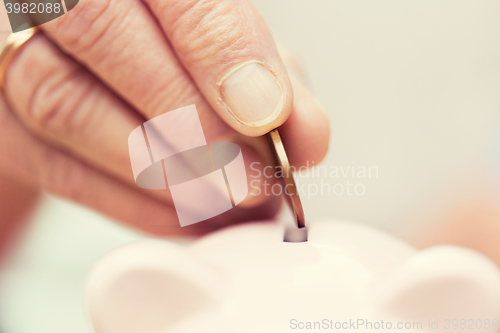 Image of senior woman hand putting money to piggy bank