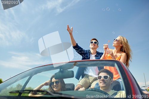 Image of friends driving in car and blowing bubbles