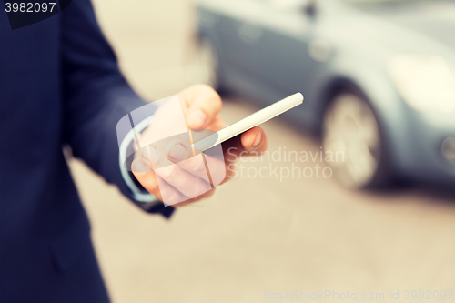 Image of close up of man hand with smartphone and car