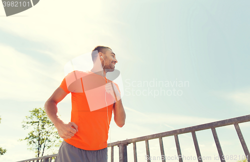 Image of happy man with earphones running outdoors