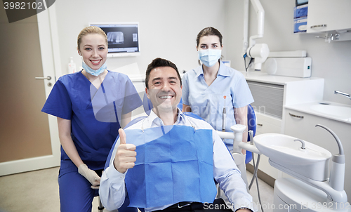 Image of happy female dentists with man patient at clinic