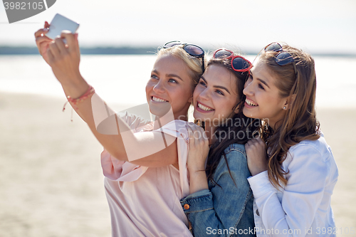 Image of group of smiling women taking selfie on beach