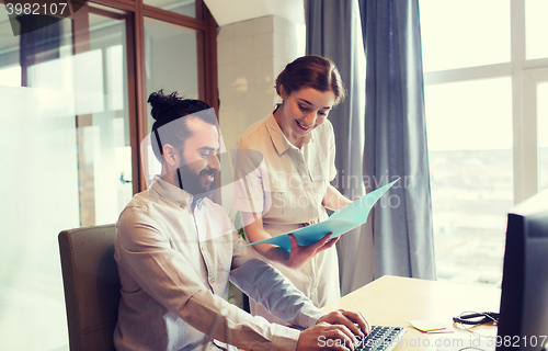 Image of happy creative team with computer in office
