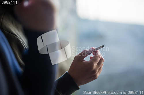 Image of close up of male hand with smoking cigarette