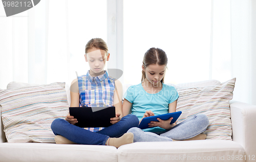 Image of girls with tablet pc sitting on sofa at home