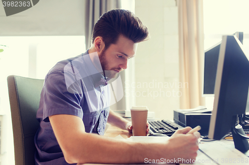 Image of creative male office worker with coffee writing