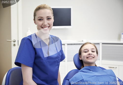 Image of happy female dentist with patient girl at clinic