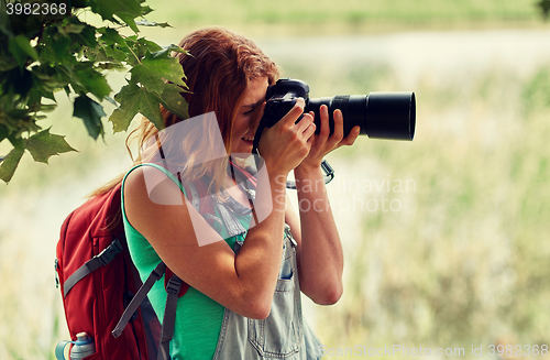 Image of young woman with backpack and camera outdoors