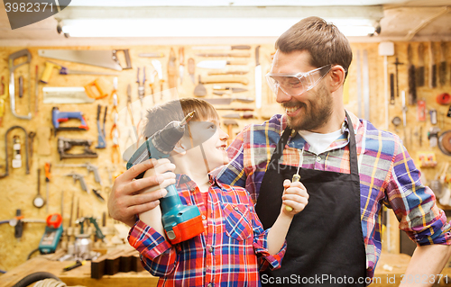 Image of father and son with drill working at workshop